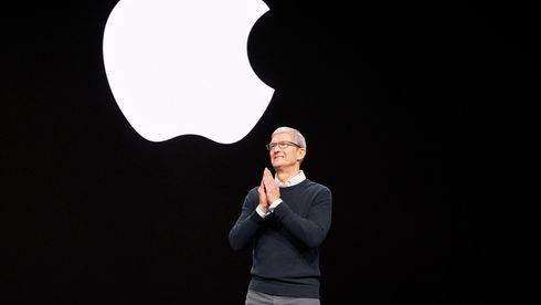 Cook i genser med skjorte under, stående foran en svart bakgrunn med Apple-logoen på
