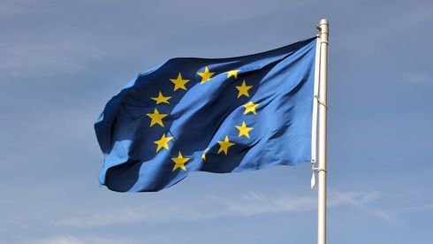 Et EU-flagg vaier i vinden foran blå himmel