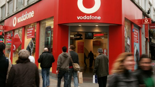 Personer som går forbi en Vodafone butikk.