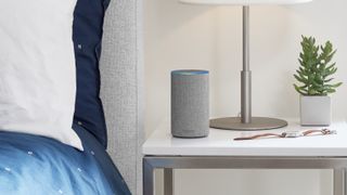 En grå smart-høytaler merket Amazon står på et nattbord.