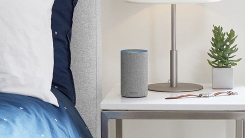 En grå smart-høytaler merket Amazon står på et nattbord.
