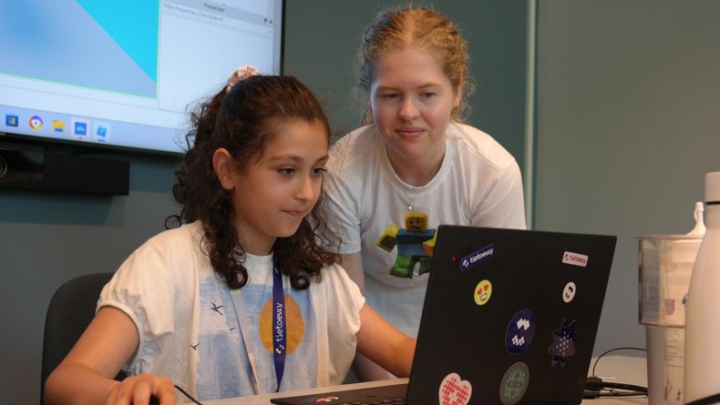 En ung kvinne og ei jente i 10 årsalderen ser på en laptop.