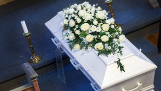 Kiste med blomster på i begravelse.