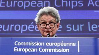 Thierry Breton titter over brillene bak talerstolen i EU-kommisjonen.