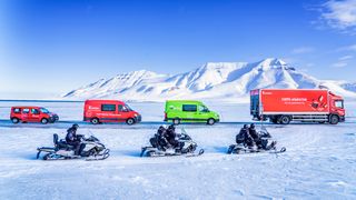 Ulike postbiler på Svalbard, snødekte fjell i bakgrunnen.