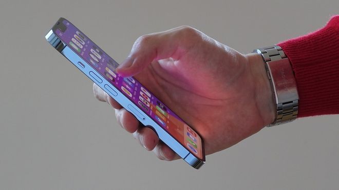 Person holder en Iphone 13 Pro i hånden.