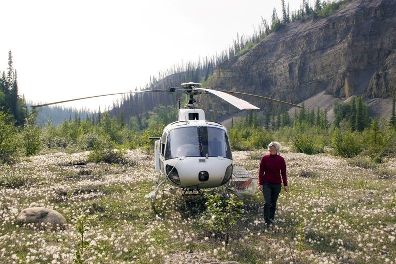 Annique van der Boon foran helikopter som står plassert på en eng i fjellheimen.