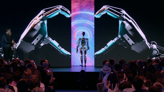 En robot står midt på en scene med robothender på skjerm på begge sider.