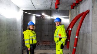 Mona Nyberg og Pål Høylie i området hvor protonstrålen skal presses inn i beamlinen. På veggen ser du noen av de mange gjennomføringsrørene for kabler gjennom de tykke betongveggene. I bakgrunnen er det over 9 meter høye rommet hvor syklotronen skal installeres.