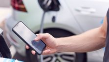 man leser på mobilen mens bilen lades.