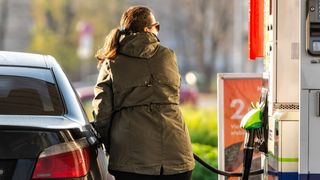 Kvinne fyller drivstoff på bilen.