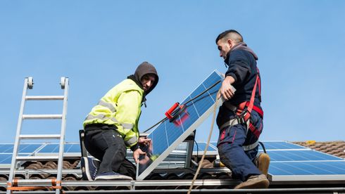 To menn på et tak og legger ned solceller